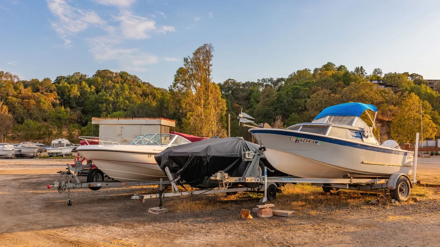 Several boats on trailers parked in an outdoor storage yard